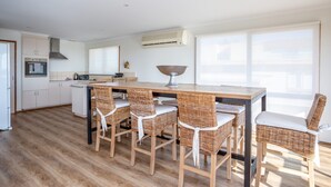 Cozinha moderna com uma ilha central, quatro cadeiras de vime e uma janela ampla que oferece luz natural.