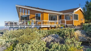 A modern house with a balcony, large windows, and a view of the surrounding landscape.