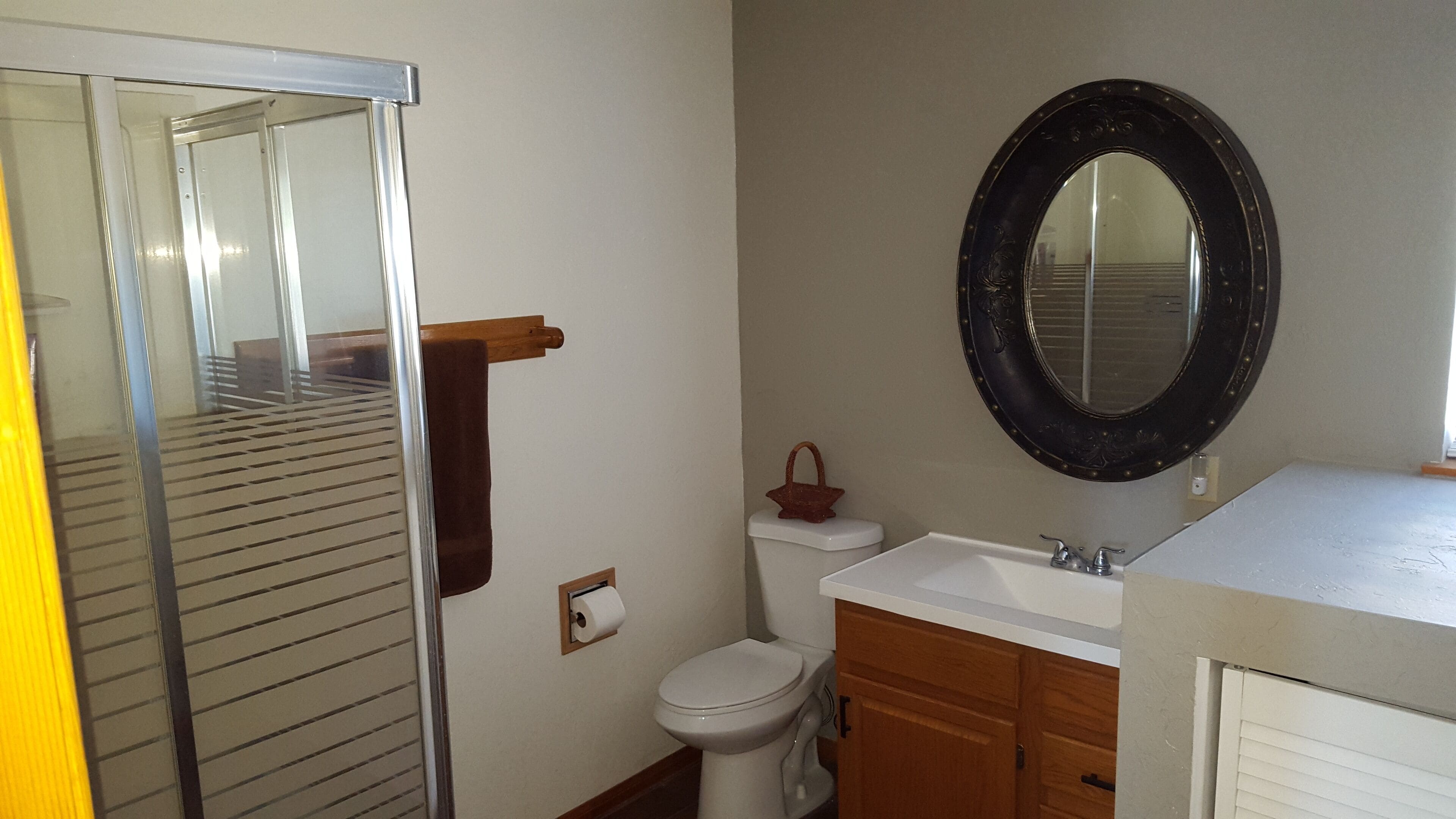 A bathroom with a toilet, sink, mirror, and towel rack.