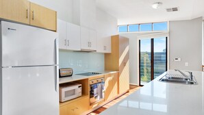A modern kitchen with a refrigerator, microwave, oven, and a large window providing a view of the outside.