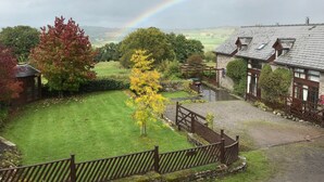 A rural landscape with a house, a rainbow, and a grassy area.