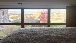 A room with a large window offering a view of a rural landscape, including fields and a distant building.