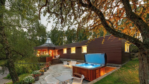 Une cabane en bois avec un jacuzzi, un espace salon extérieur et un jardin.