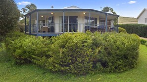 Residential building with a covered porch and lush green surroundings.