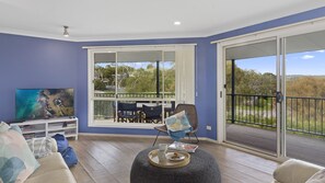 Relax in this inviting living space with a large TV, comfortable sofa, and a balcony offering a view of the outdoors.