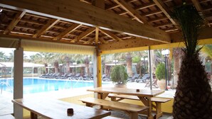 An outdoor pool area with wooden benches and a view of the pool. - One of the biggest Villas Near Athens Greece 40% off January 1 to May 15 (ANAVISSOS)