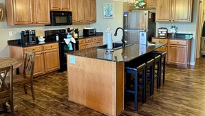 A kitchen with wooden cabinets, a central island, a refrigerator, and a coffee maker. - 3 BR, 3 Bth, Vickery Resort Lower level with walkout to the lake. (Hollister)