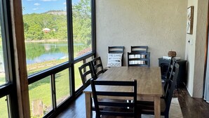 A dining area with a wooden table and chairs, a ceiling fan, and large windows overlooking a lake. - 3 BR, 3 Bth, Vickery Resort Lower level with walkout to the lake. (Hollister)