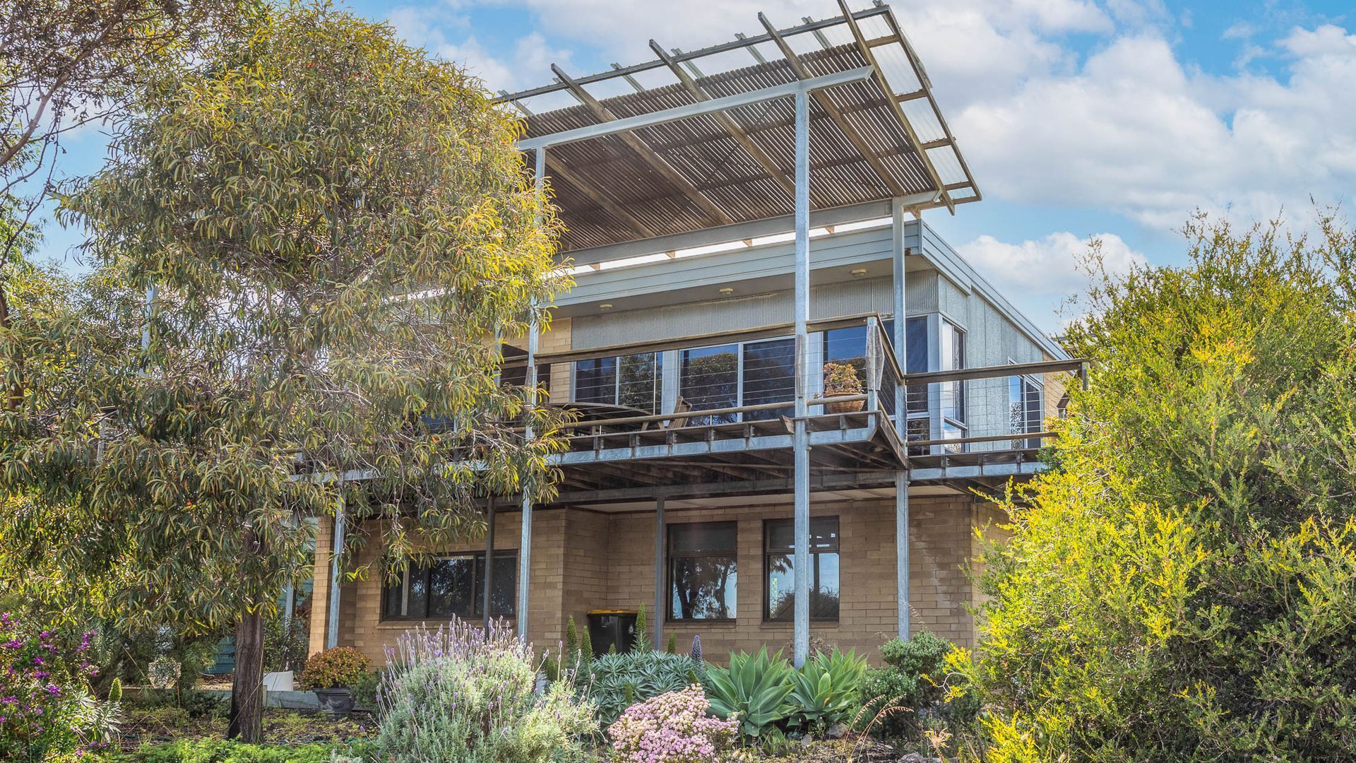 A modern two-story building with a balcony and a pergola.