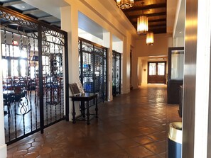 Stroll through the elegant corridor, lined with ornate gates and leading to a dining area with a wooden bench.