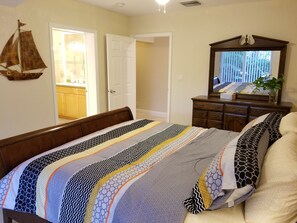 Un dormitorio con una cama, un tocador, un espejo y una decoración de velero en la pared.