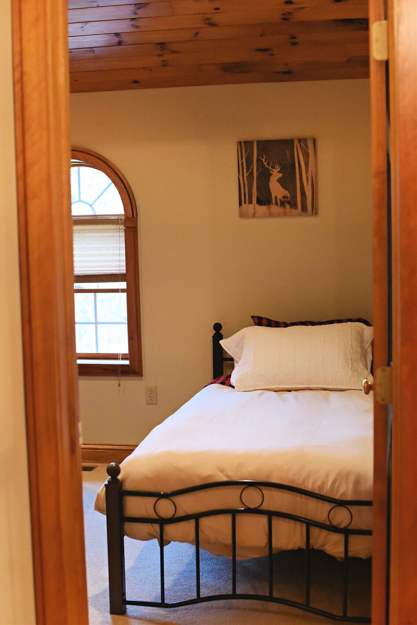 A bedroom with a bed, a window, and a painting on the wall.