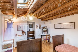 Un dormitorio con techo de madera, una cama, un escritorio y una silla.