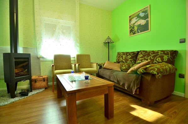 A living room with a sofa, chairs, a coffee table, a fireplace, and a painting on the wall.