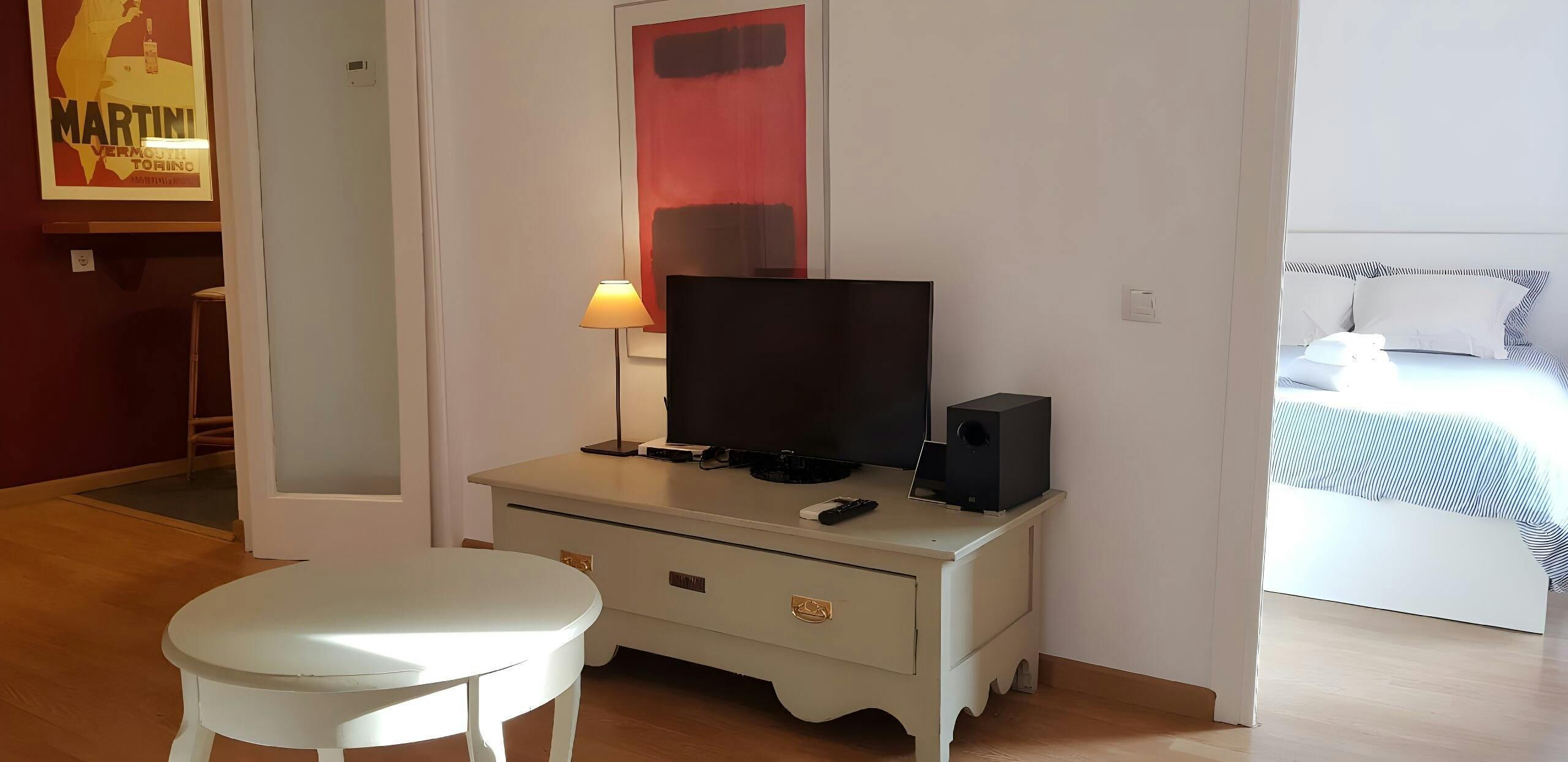 Ein Hotelzimmer mit einem Bett, einem Fernseher auf einer Kommode, einer Lampe und einem Bild an der Wand.