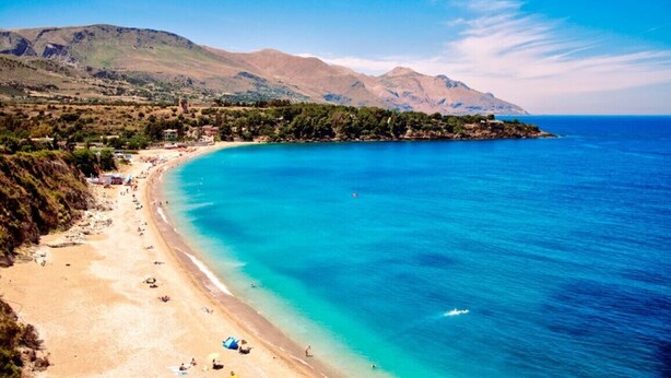 A coastal beach with clear turquoise waters, a sandy shore, and a mountainous backdrop. - Guidaloca Bay House Scopello with mini-pool (Castellammare del Golfo)