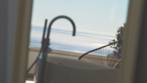Una ventana con vista al mar y un árbol.