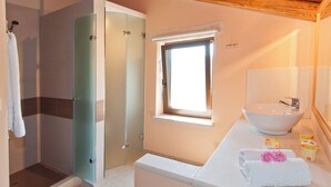 Un baño con ducha de vidrio, lavamanos y ventana.