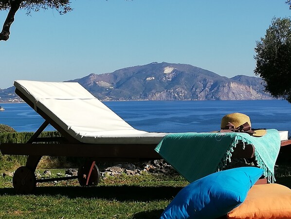 A beachside lounge with a view of the sea and mountains.