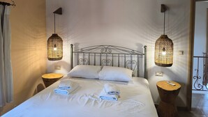 Un dormitorio con cama, dos mesitas de noche, lámpara colgante y unidad de aire acondicionado.