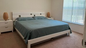 Quarto com cama, duas mesas de cabeceira e janela com persianas.