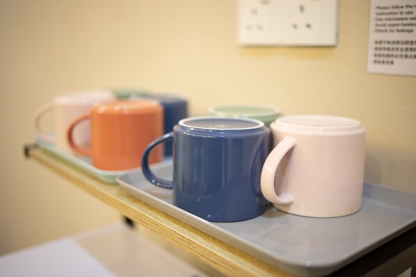 Une étagère avec différentes tasses de couleurs variées.