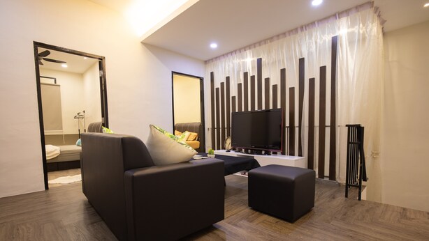 A modern living room with a sofa, ottoman, and a flat-screen TV. - Casa Le Rock (Langkawi)