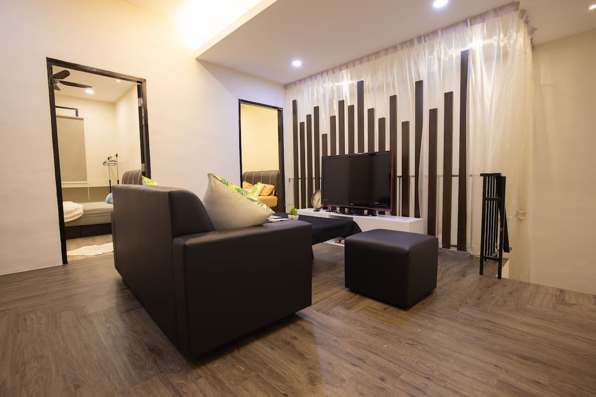 A modern living room with a sofa, ottoman, and a flat-screen TV.