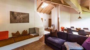 A modern living room with a sofa, a dining table with chairs, and a wooden ceiling. - 100sqm apartment in central location in Lutago with three rooms (Lutago)