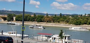 Enjoy a serene riverside view with a bridge and boats on the water, and access to a pedestrian walkway.