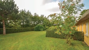 A well-maintained garden with a lawn, hedges, and a variety of trees.