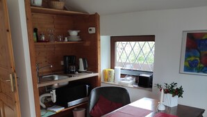 A cozy kitchen with wooden shelves, a dining table with red placemats, and a window with a view of greenery. - Hamburg Rahlstedt / Farmsen, small but very fine (Wandsbek)