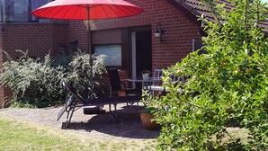 A patio with a red umbrella, outdoor furniture, and a potted plant. - Hamburg Rahlstedt / Farmsen, small but very fine (Wandsbek)