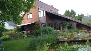A modern house with a sloped roof, a patio with outdoor furniture, and a pond. - Hamburg Rahlstedt / Farmsen, small but very fine (Wandsbek)