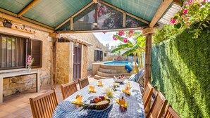 Un espace extérieur abrité, aménagé pour les repas, avec une piscine, des murs en pierre et un mur végétal.