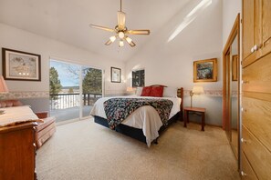 Ein Schlafzimmer mit einem großen Bett, einem Deckenventilator, einer Kommode und Blick ins Freie.