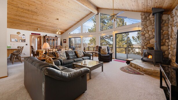 A spacious living room with a fireplace, leather sofas, and a stone wall.
