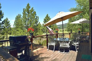 Eine Holzterrasse mit Gartenmöbeln, darunter ein Tisch, Stühle und ein Grill.