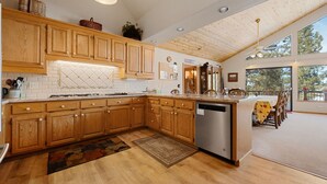 A spacious kitchen with wooden cabinets, a dishwasher, and a dining area with a table and chairs.