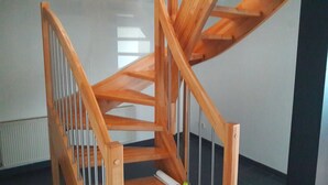 A wooden staircase with a handrail and a metal balustrade.