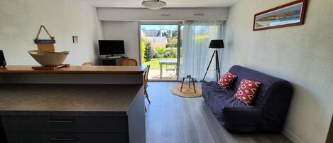 Un salon moderne comprenant un canapé, un téléviseur et un coin repas avec une table et des chaises.