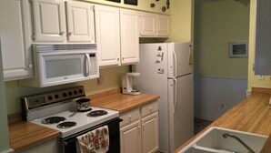 A compact kitchen with white cabinets, a microwave, a stove, a refrigerator, and a sink. - Escape To Madeline Island !  Superior Lakefront 2 Bedroom Condo  (La Pointe)