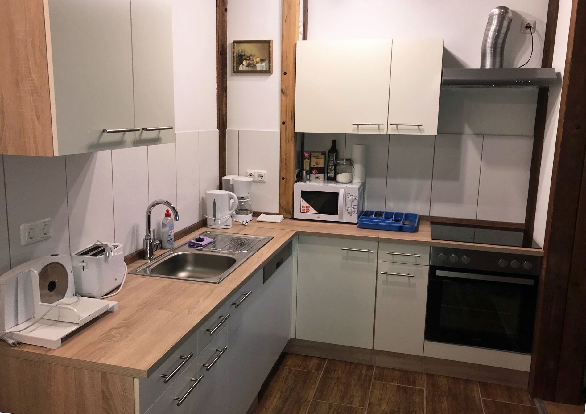 Una cocina compacta con un lavamanos, una cafetera, un microondas y una estufa.