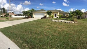 A residential house with a front yard, driveway, and a garage. - Charmer in the Heart of Cape Coral (Cape Coral)