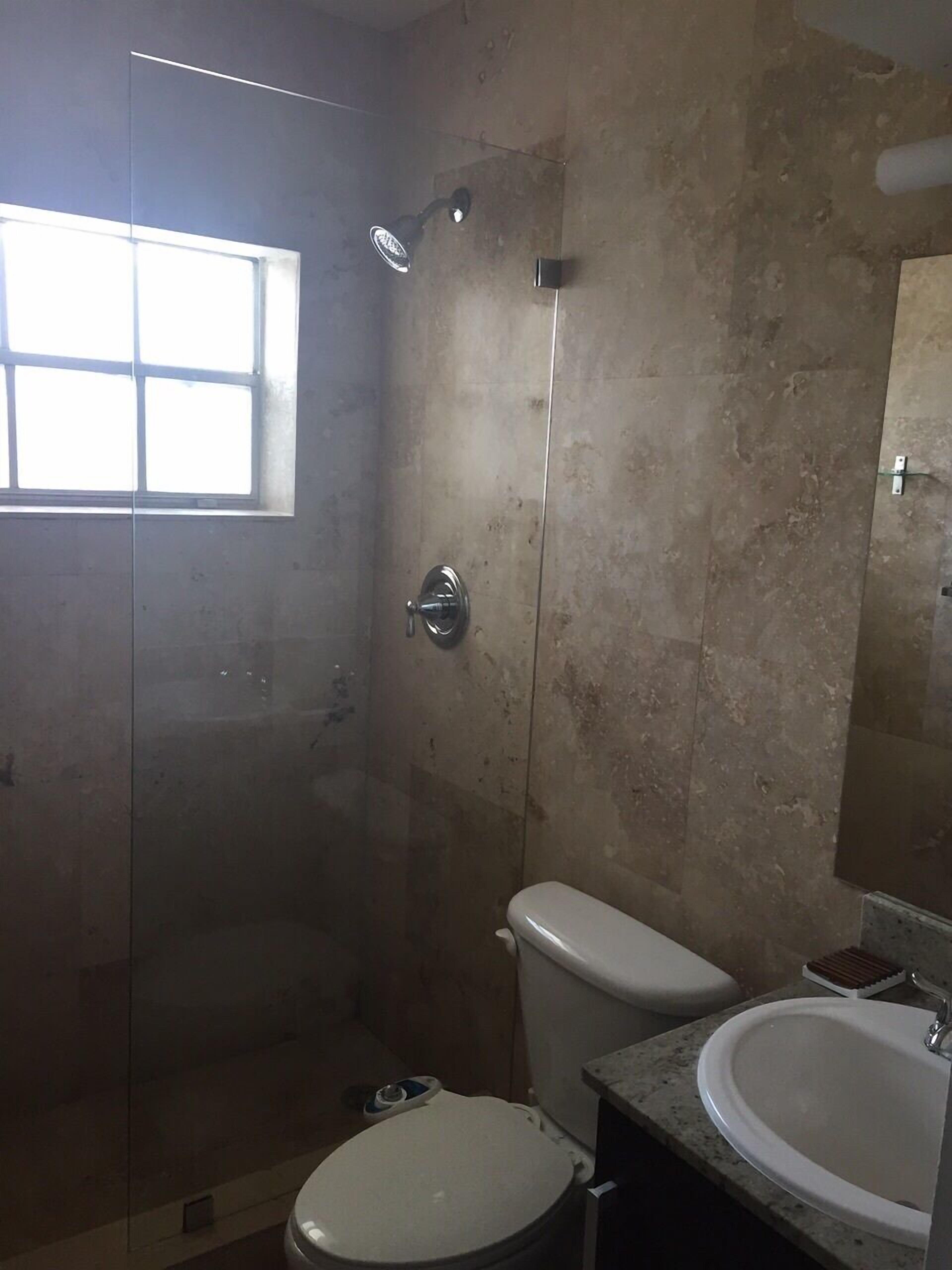 Ein Badezimmer mit Glasdusche, Toilette und Waschbecken.
