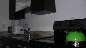 A kitchen with a microwave, sink, and coffee maker.