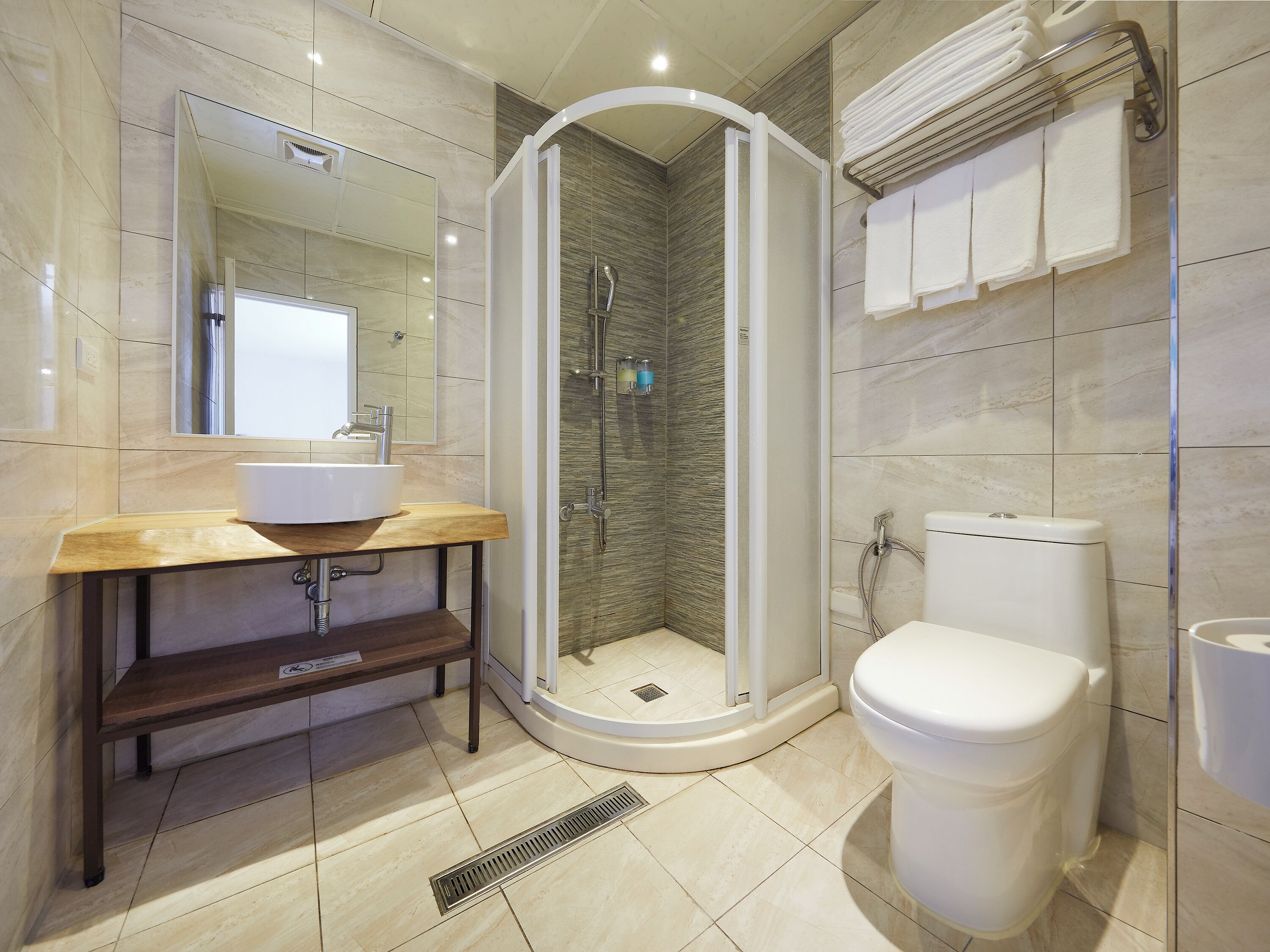 A modern bathroom with a curved shower enclosure, a sink with a wooden vanity, and a toilet.