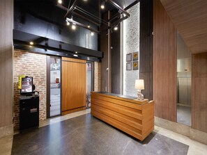 A reception desk with a wooden finish, a check-in kiosk, and a wall-mounted refrigerator. - CHECK inn Yilan LuoDong (Luodong)