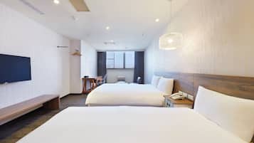 A hotel room with two beds, a flat-screen TV, a desk, and a large window.