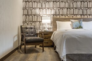 A bedroom with a wooden headboard, a leather chair, a bedside table with a lamp, and a bed with white bedding and a decorative pillow. - CHECK inn Yilan LuoDong (Luodong)